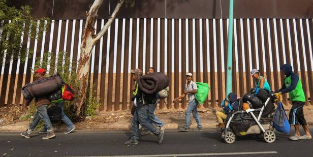 Migrantes centro-americanos caminham nesta terça-feira em Mexicali (México) ao lado da cerca na fronteira com os EUA. JUAN BARAK EFE